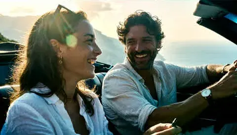 6. Maya and Leo laugh in the convertible, the sun behind them